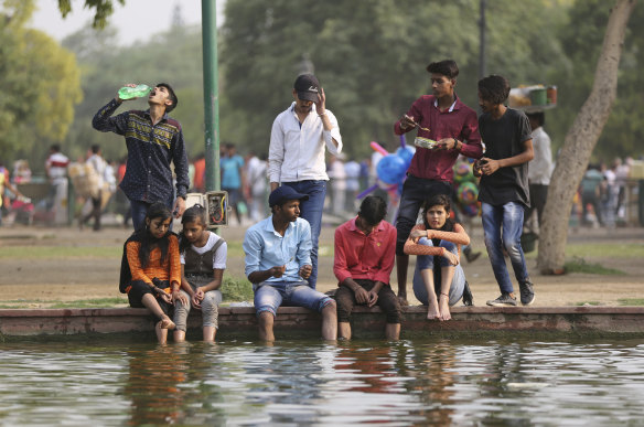Indians sit on the edge of a pond near the India Gate monument on a hot day in New Delhi when the mercury climbed to 45 degrees in May 2018.
