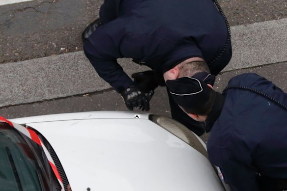 Policemen look at a bullet impact on a car after Paris terror attack.