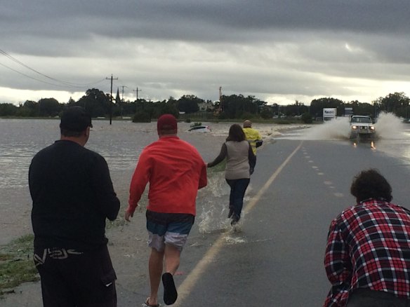 Rescuers rush to a car that is stranded in flood waters in Maitland.