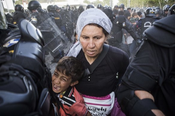 A woman and child flee as police respond with force against Refugees protesting in Horgos on the Serbian/Hungarian border.