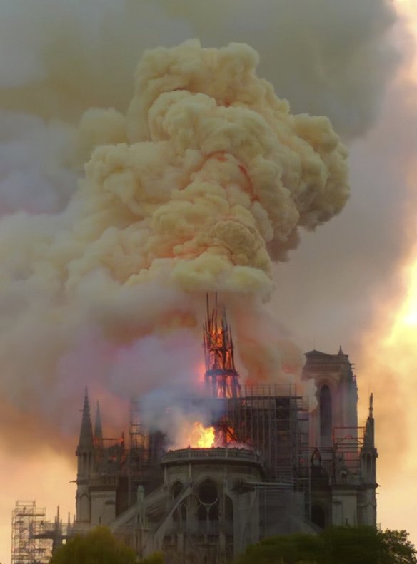 Flames and smoke rise as the spire of Notre Dame cathedral is on fire.