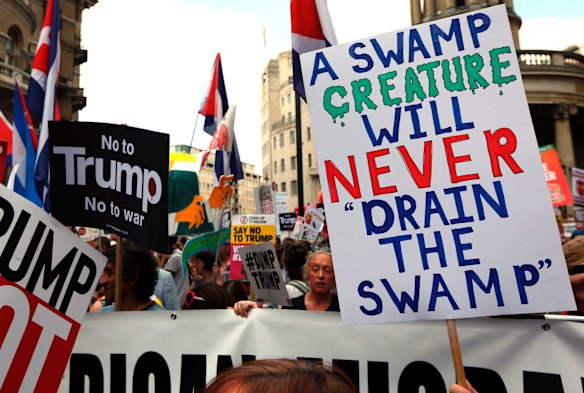 'A Swamp Creature Will Never Drain The Swamp'. Protesters hold banners during a march opposed to the visit of U.S. President Donald Trump in London, Friday, July 13, 2018. AP
