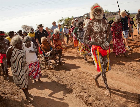 July 19th 2011,  Covered in Ochre for ceremony, Chief law man Jacob Nayinggul is pushed in his wheelchair by ANU hitorian Martin Thomas as he supervises proceedings as human remains are finally reurned to their ancestral home in Gunbalanya for reburial after over 60 years in the posession of the Smithsonian Institution after being collected during a combined Australian and American expedition to Arnhem Land in 1948.