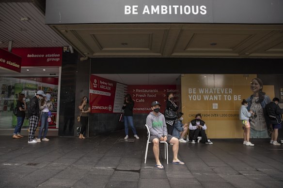 Haymarket local, Zeindy Vannyna brings a kitchen chair after already waiting 2 hours for a COVID-19 PCR test in Sydney's CBD on Tuesday, December 28, 2021.