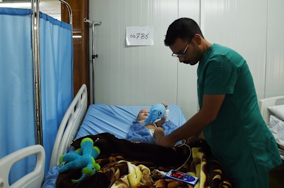 Nurse Ameen Tahsin (right) treats Qasid Radhwan 11 months old (left) in the Athba Field Hospital where he is being treated for shrapnel injuries. 