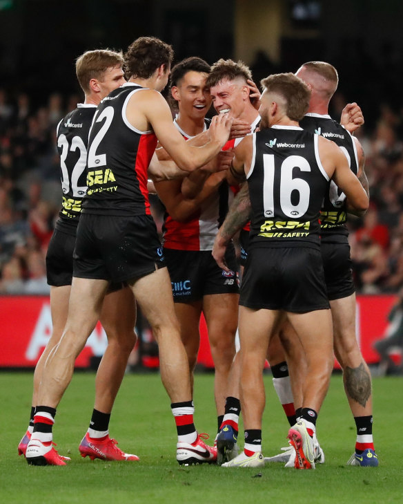 Jack Hayes is swarmed by teammates after kicking a goal on debut.