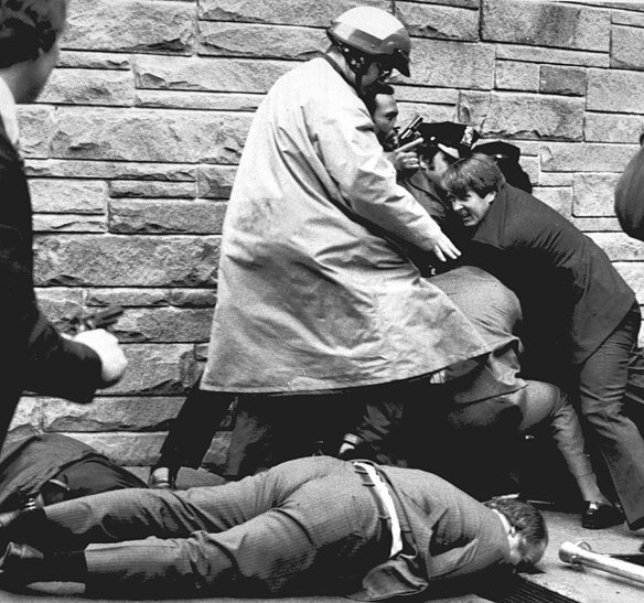 James Brady, president Reagan’s press secretary, lies wounded on the footpath as Secret Service agents and police wrestle John Hinckley jnr to the ground after the shooting in 1981.