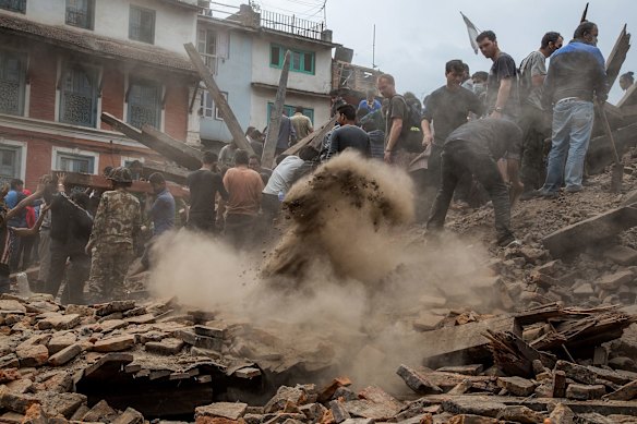 Emergency workers and bystanders clear debris while searching for survivors under a collapsed temple in Basantapur Durbar Square following an earthquake in Kathmandu, Nepal. 