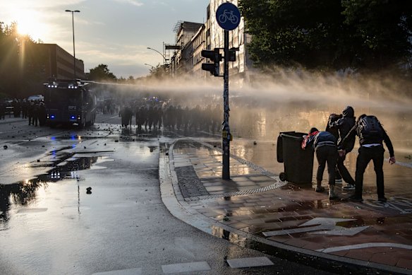 HAMBURG, GERMANY - JULY 07: Demonstrators try to protect themselves behind a garbage can for the police water cannon during a demonstration against the G20 Summit on July 6, 2017 in Hamburg, Germany. Leaders of the G20 group of nations are arriving in Hamburg today for the July 7-8 economic summit and authorities are bracing for large-scale and disruptive protest efforts. (Photo by Thomas Lohnes/Getty Images)