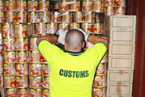 Customs officer with some of the huge haul of ecstasy tablets forund hidden in tomato tins.