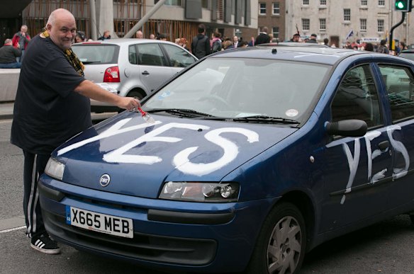 Yes supporter James McLeod paints his Fiat Punto car parked outside the Scottish Parliament.