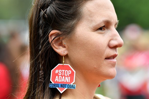 A protestor is seen wearing Stop Adani earrings at the anti-Adani coal mine rally at Crosby Park in Brisbane.