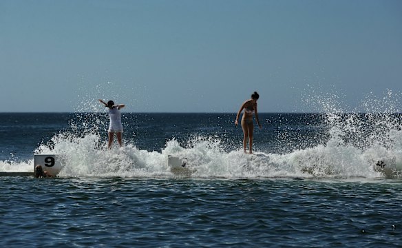 People take on the waves splash over the diving blocks at Merewether Ocean Baths.