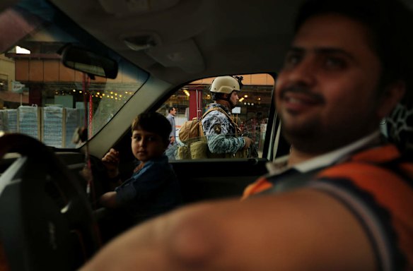 On the day where 6 bombings occured in Baghdad, a car stops in traffic as Iraqi policeman Adnan Lugaylee 29  (center) provides security at the Al-Rahibat traffic control checkpoint in Karada area in Baghdad.