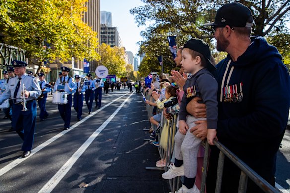 Brad Gardner with son Maxwell, 2, wearing Grand dad's medals, watch the ANZAC Day march down Elizabeth St, Sydney.