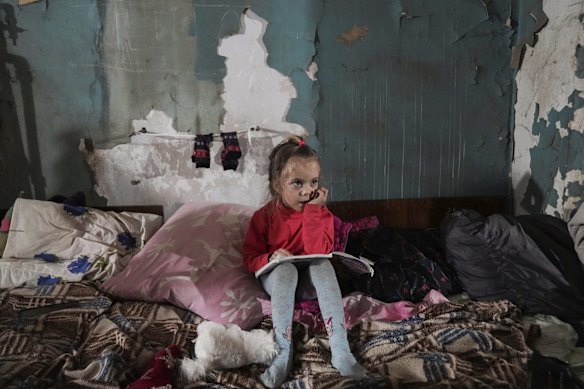 A girl sits in an improvised bomb shelter in Mariupol, Ukraine.