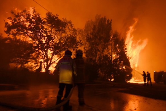 Firefighter from fbnsw stumbles after being hit in smoke and helped back to safety as Gospers mt fire crosses bells line. Late on December 21, 2019. 