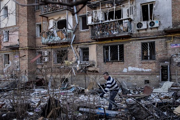 A man throws out broken windows from his apartment in front of a residential apartment complex that was heavily damaged by a Russian attack in Kyiv. An estimated half of Kyiv's population has fled to other parts of the country, or abroad, since Russia invaded on February 24.