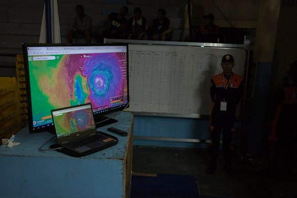 Screens display meteorological forecasts as an official stands by in a gym ahead of Typhoon Mangkhut's arrival in Tuguegarao, Cagayan province, the Philippines, on Friday, Sept. 14, 2018. Philippines authorities are evacuating thousands of people in the path of Super Typhoon Mangkhut to safer grounds hours before the cyclone slams into the countryâs northern provinces. Photographer: Carlo Gabuco/Bloomberg