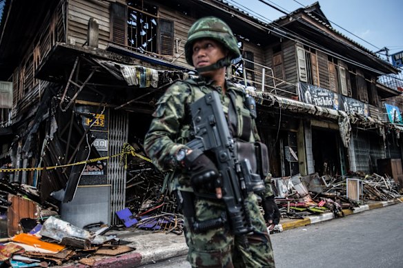 Thai soldiers on alert at the burnt out remains of a timber shop burnt down after insurgents bombed it in mid May. 