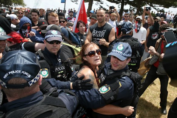 A woman who spoke against people from the anti-racism rally is brought away by the police as the crowd started getting hostile towards her during the march along the beach in Cronulla.