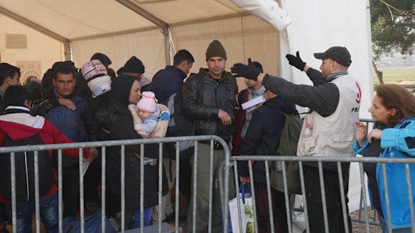 Refugees queue for buses.