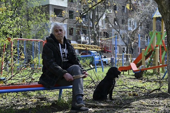 Physical education teacher Nikolai, 89, sits with his dog in a yard of an apartment building destroyed by night shelling in Kramatorsk.