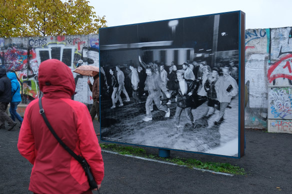 A visitor looks at a photograph from 1989 at Bernholmer Bridge.
