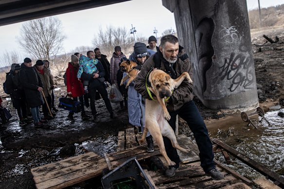 A man carries his dog as he flees fighting in Irpin.