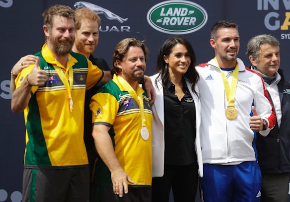 Britain's Prince Harry and Meghan, Duchess of Sussex pose for a photograph with medal winners at the Invictus Games driving challenge on Cockatoo Island in Sydney.