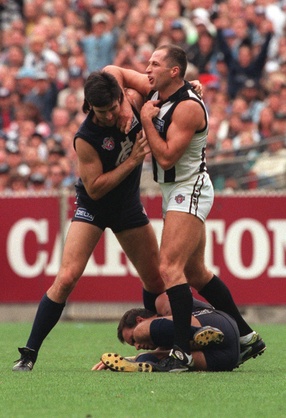 Collingwood’s Craig Kelly tangles with Carlton captain Stephen Kernahan.   Greg Williams lies on the ground.