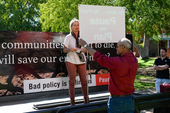 A protester holds a 'Pause the Plan' sign in front of Sussan Ley at a rally in Albury.  