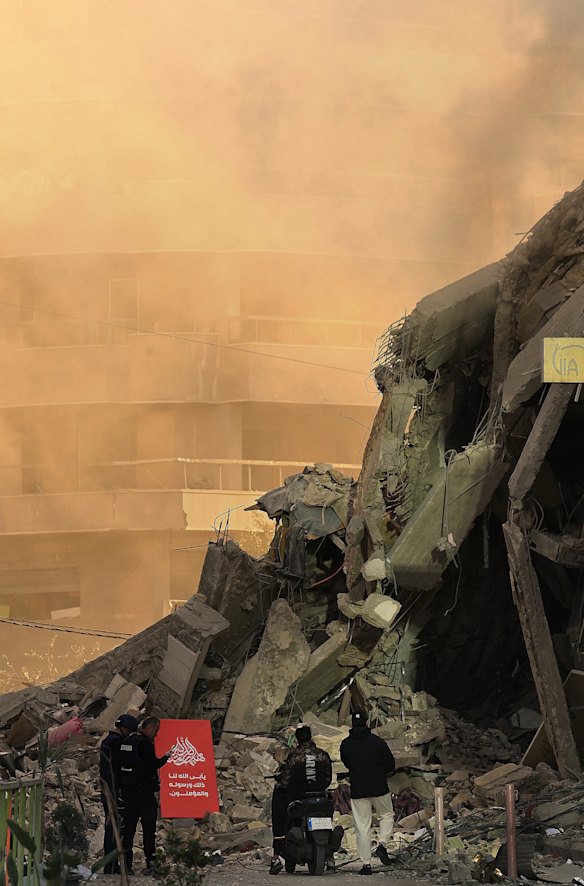 I passanti camminano vicino alla scena di un attacco aereo israeliano a Beirut.