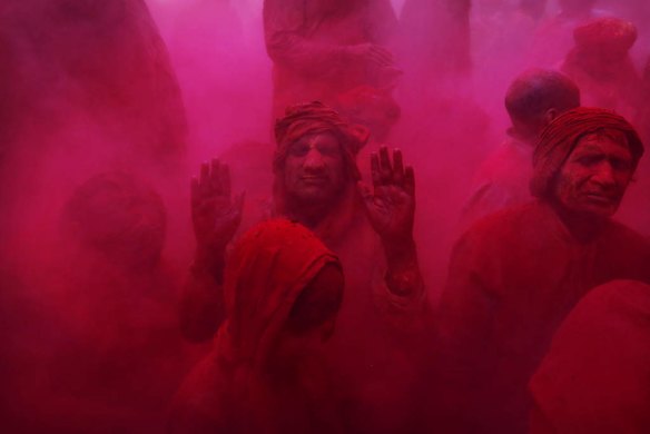Hindu men and a boy from the village of Nangaon are covered in colored powder.