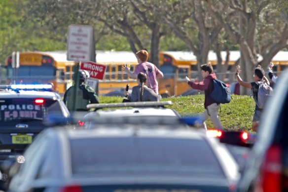 Students run with their hands in the air following the shooting.