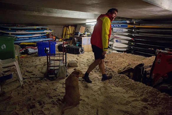 Andrew Tooher from Coogee Surf Club with dog Lana supervises the cleanup  4 hours before high tide and the water is up very high as they try to clear  sand from the Surf Lifesavers boat shed. June 6th.