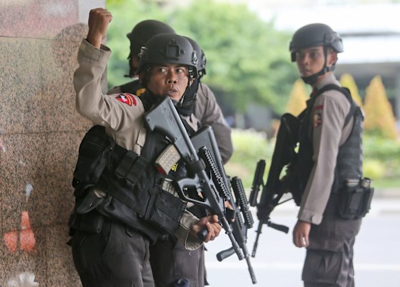 A police officer gives a hand signal to a squad mate as they search a building near the site of an explosion in Jakarta, Indonesia Thursday, Jan. 14, 2016.  Attackers set off explosions at a Starbucks cafe in a bustling shopping area of downtown Jakarta and waged gun-battles with police Thursday, leaving bodies in the streets as office workers watched in terror from high-rise windows.