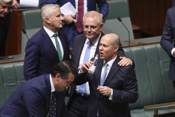 Treasurer Josh Frydenberg is congratulated by Prime Minister Scott Morrison and other colleagues after delivering the budget.