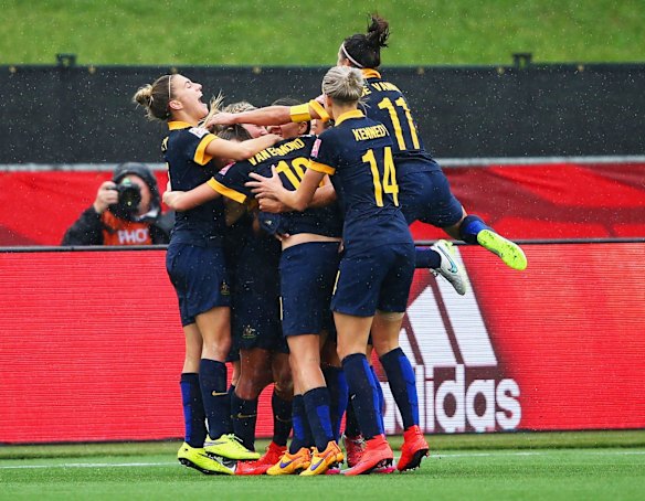 Kyah Simon of Australia (obscured) is mobbed by team mates in celebration.
