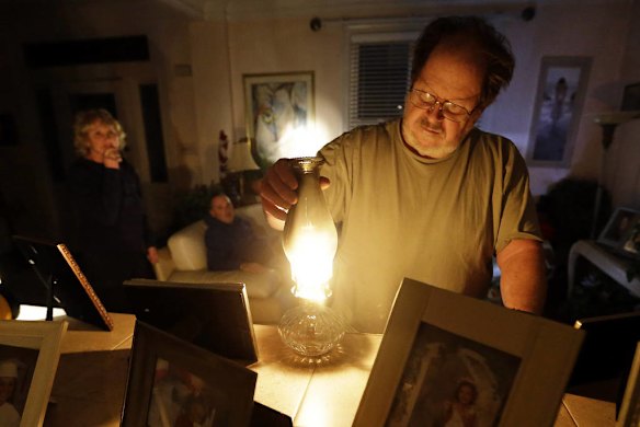 Jeff Willard lights a candle in his living room as his girlfriend, Diana Conte, back left, and her son, Ricky, wait for electricity to return in Ventnor City, N.J.,
