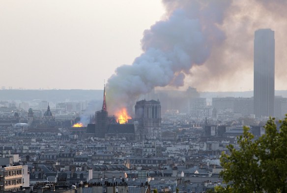 Massive plumes of yellow brown smoke is filling the air above Notre Dame Cathedral.