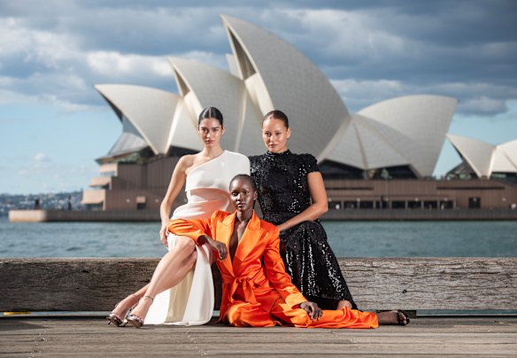 Marisa Pavela, Miji Awakyr and Cameron Stephens pose in front of the Sydney Opera House wearing Carla Zampatti.