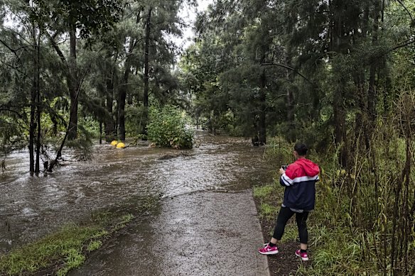 A person is seen next to the overflowing Nepean River at the Penrith weir.