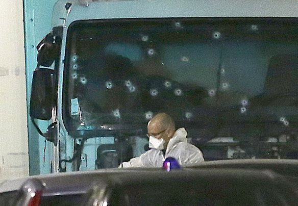 A forensic officer stands near the van with its windscreen riddled with bullets.