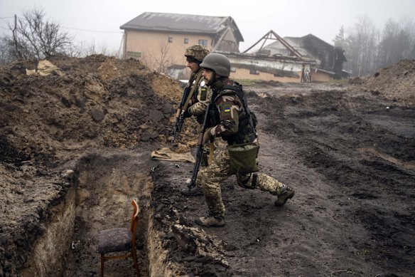Ukrainian soldiers approach a trench that had been used by Russian soldiers as they retake an area on the outskirts of Kyiv.