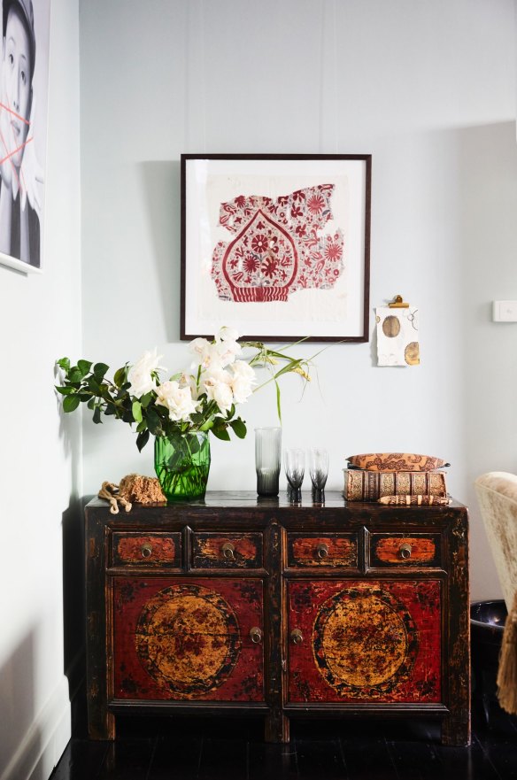A framed vintage trading cloth bought by the couple on their honeymoon in Sri Lanka hangs above an ornate Mongolian cabinet. The small, unframed artwork is by Amber