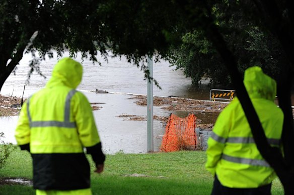 Two onlookers at a low bridge that was closed due to flooding in Queanbeyan.