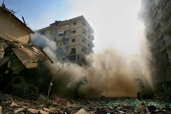 On day 27 of the Israeli-Hezbollah war, two men run through the rubble after Israeli drones are heard in the area of Dahia in the southern suburbs of Beirut. The shops and apartment buildings in the background were hit by approximately 7 Israeli bombs at 5am in the morning. 7th August 2006. 