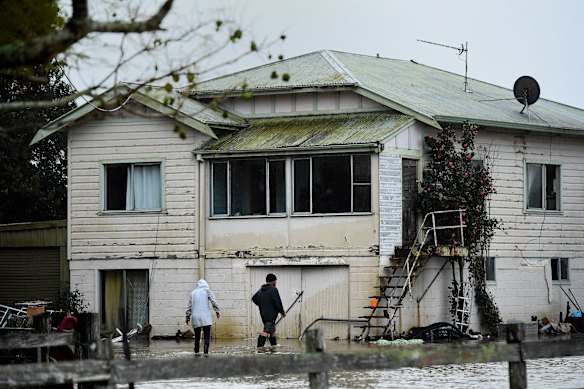 Amanda and Greg Soper walk through the floodwaters on their property near Shoalhaven Heads, NSW. 