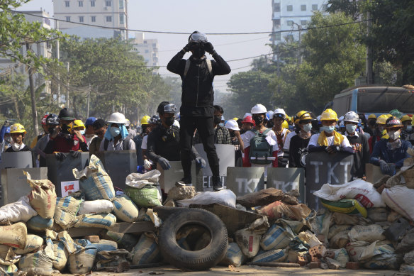 Protesters take positions behind a barricade as police gather in Yangon in March.